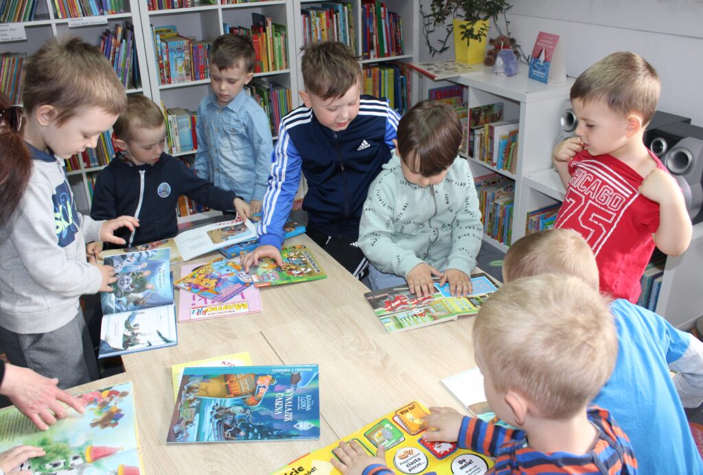 Zdjęcie przedstawia dzieci przeglądające książki 