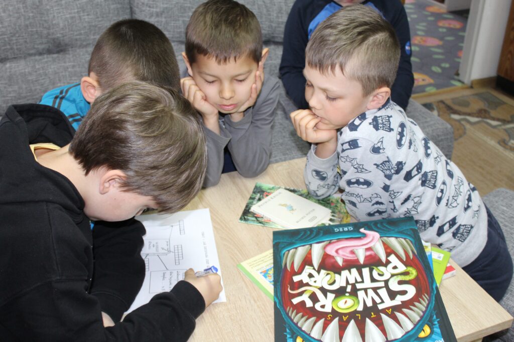 Zdjęcie przedstawia uczniów rozwiązujących zagadki.