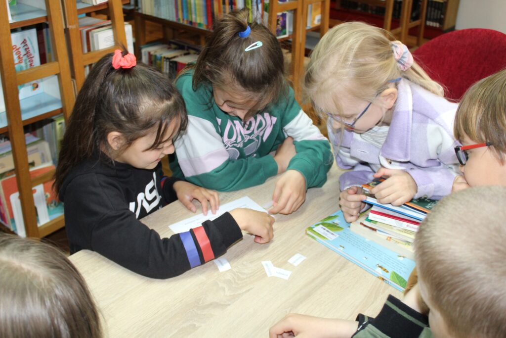 Zdjęcie przedstawia uczniów rozwiązujących zagadki.