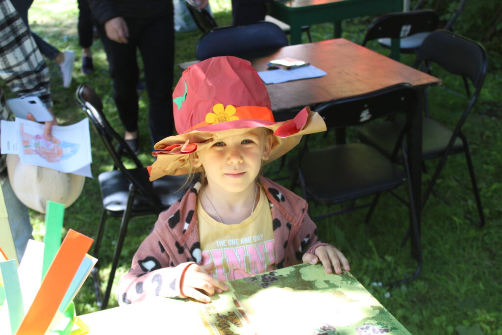 Na zdjęcia dziewczynka z własnoręcznie wykonanym, podczas warsztatów, kapeluszem.