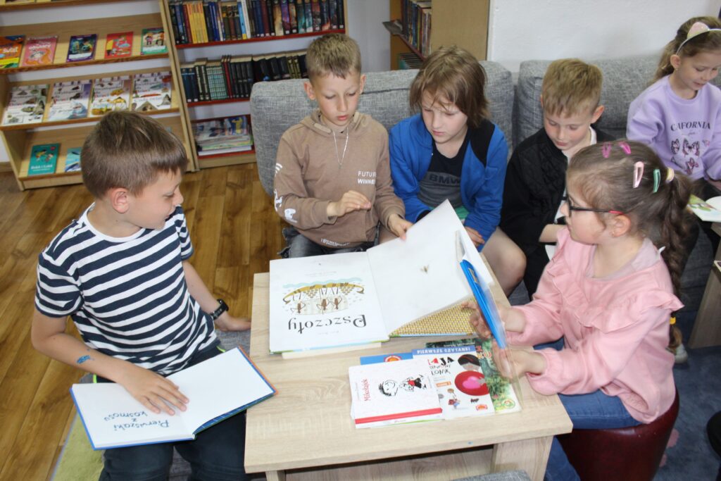 Na zdjęciu grupka dzieci czyta książki.
