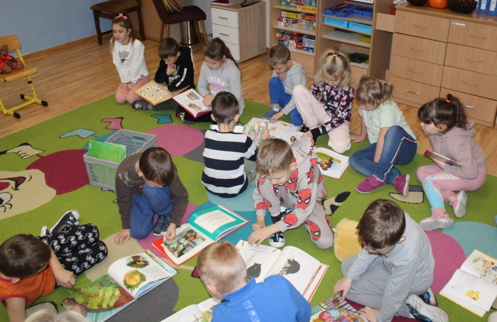 Zdjęcie przedstawia przedszkolaków czytających książki o misiach.