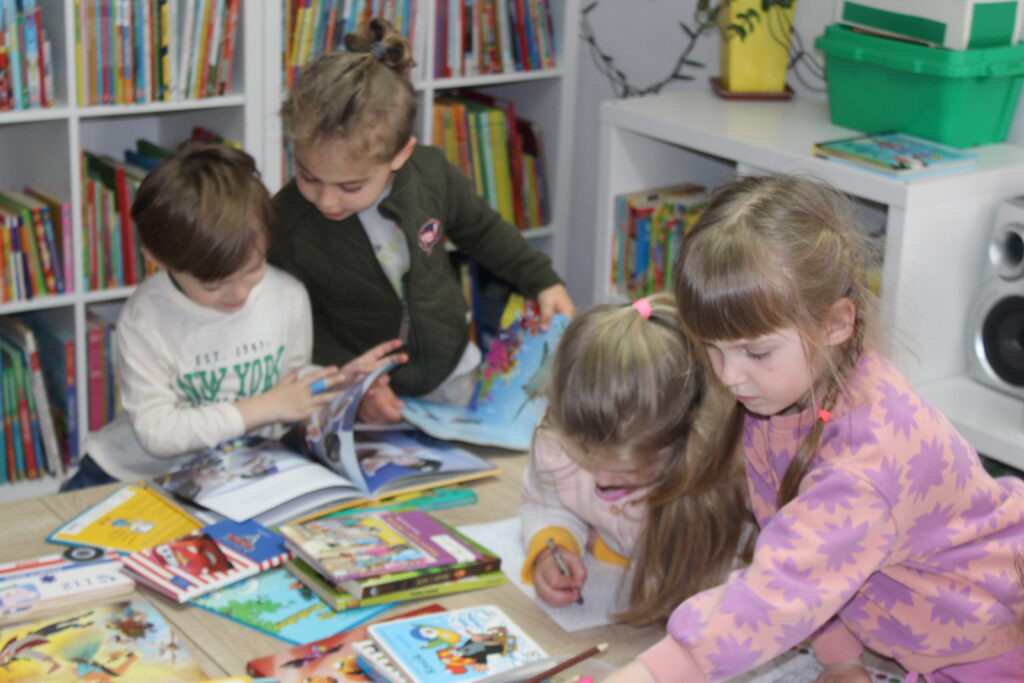 Na zdjęciu dzieci oglądające kolorowe książeczki.