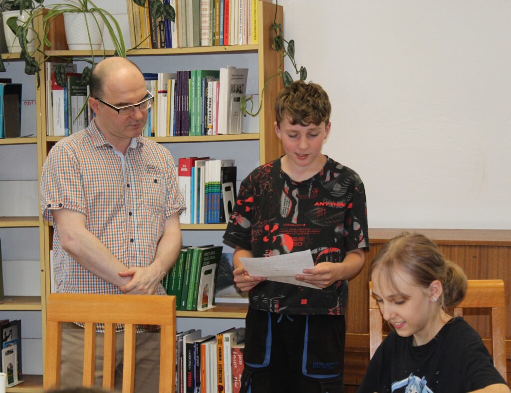 Na zdjęciu prowadzący warsztaty, Daniel Odija z uczestnikami zajęć podczas czytania napisanych przez dzieci legend.