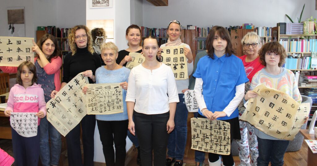 Na zdjęciu uczestnicy warsztatów z kaligrafii chińskiej z prowadzącą Martą Mońko.