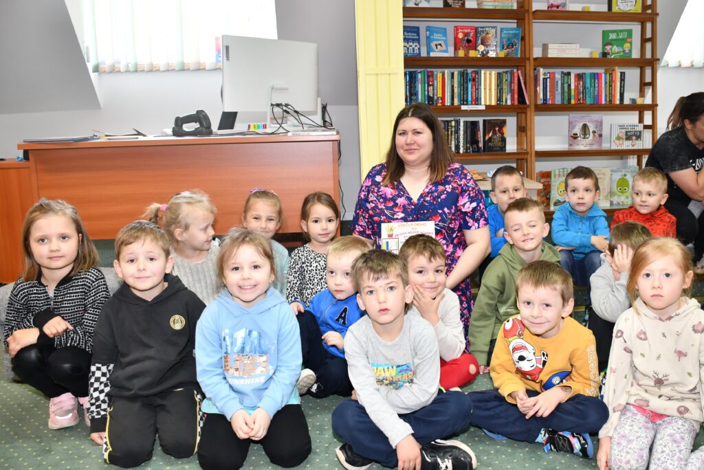 Grupowe zdjęcie przedszkolaków z panią bibliotekarką.