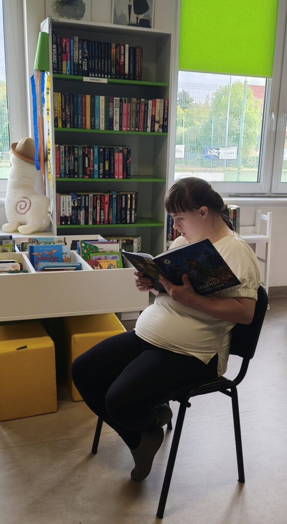Na zdjęciu podopieczna WTZ Terapeutica czytająca książkę.